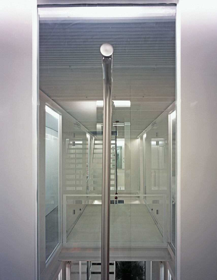 View of futuristic white stairwell with vertical stainless steel pipe in foreground
