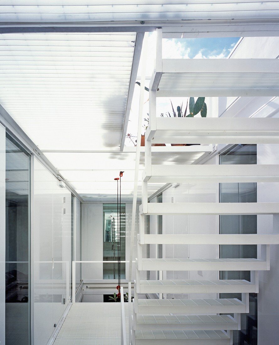 Blick von unten auf blauweissen Wolkenhimmel durch leichte Stahltreppe und auf Glasgitterboden der Dachterrasse