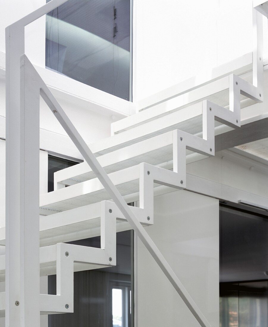 Zickzack-Stahlwange und minimalistischer Handlauf einer leichten, weissen Treppe