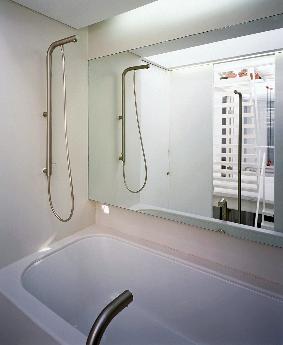Badezimmer im Spiegel gesehen über Badewanne mit Designer-Armaturen