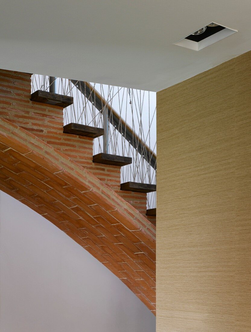 Gebogener Treppenaufgang mit schmalen Ziegelplatten, Holzstufen und Geländerbrüstung aus wilder Schnurverspannung