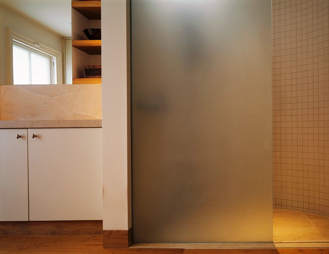 Duschwand aus satiniertem Glas in Badezimmer mit Natursteinplatten und Parkettboden