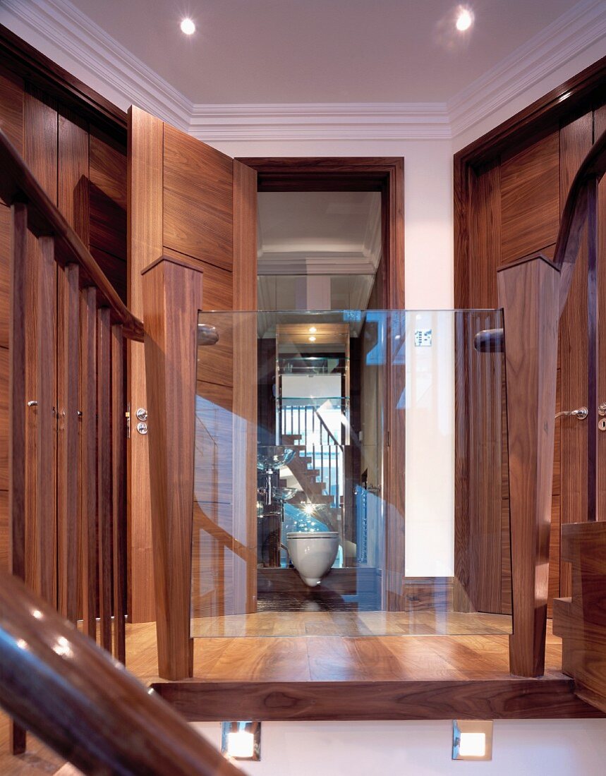 Blick durch spiegelnde Glasscheibe an Treppengeländer - Flur mit raumhohen Holztüren in englischem Wohnhaus