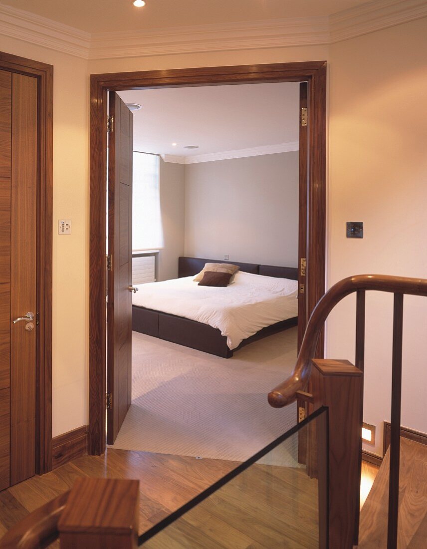 Einheitliche Holzfarbe für Türen, Boden und Treppe in Diele mit Blick in graues Schlafzimmer