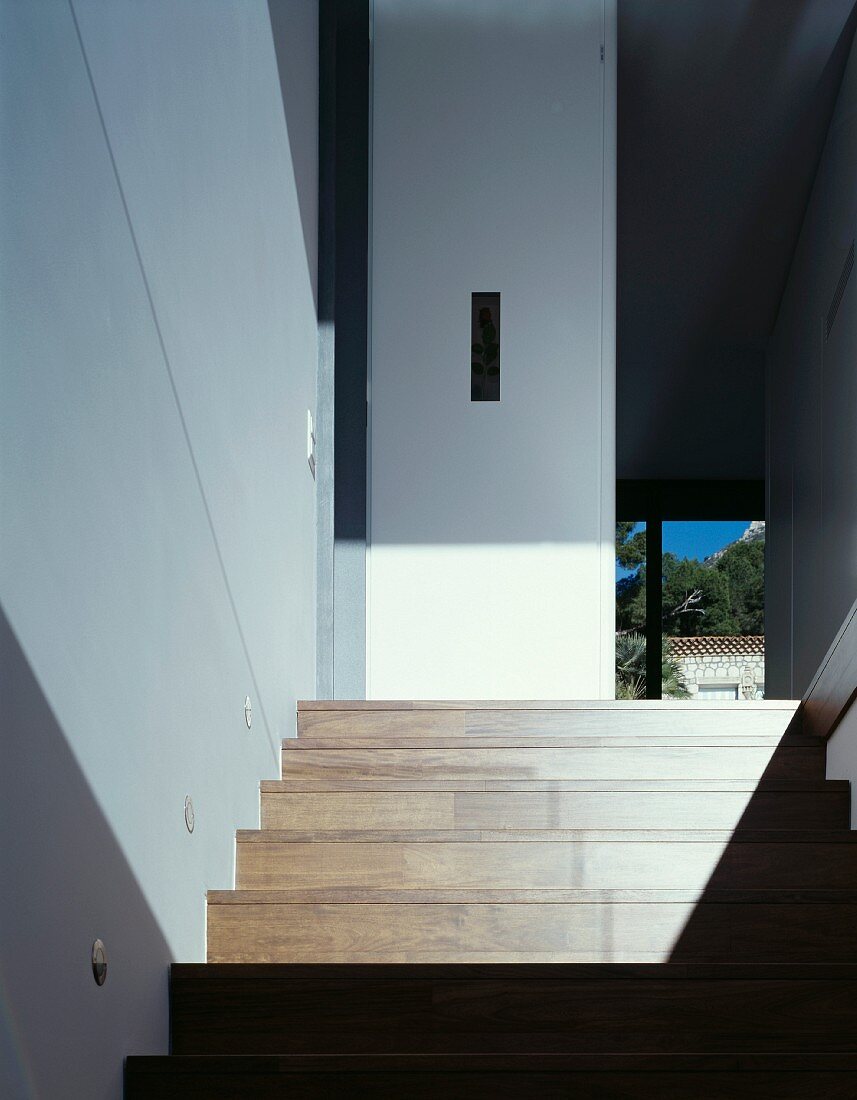 Modernes Treppenhaus mit Licht- und Schattenspiel auf Holztreppe