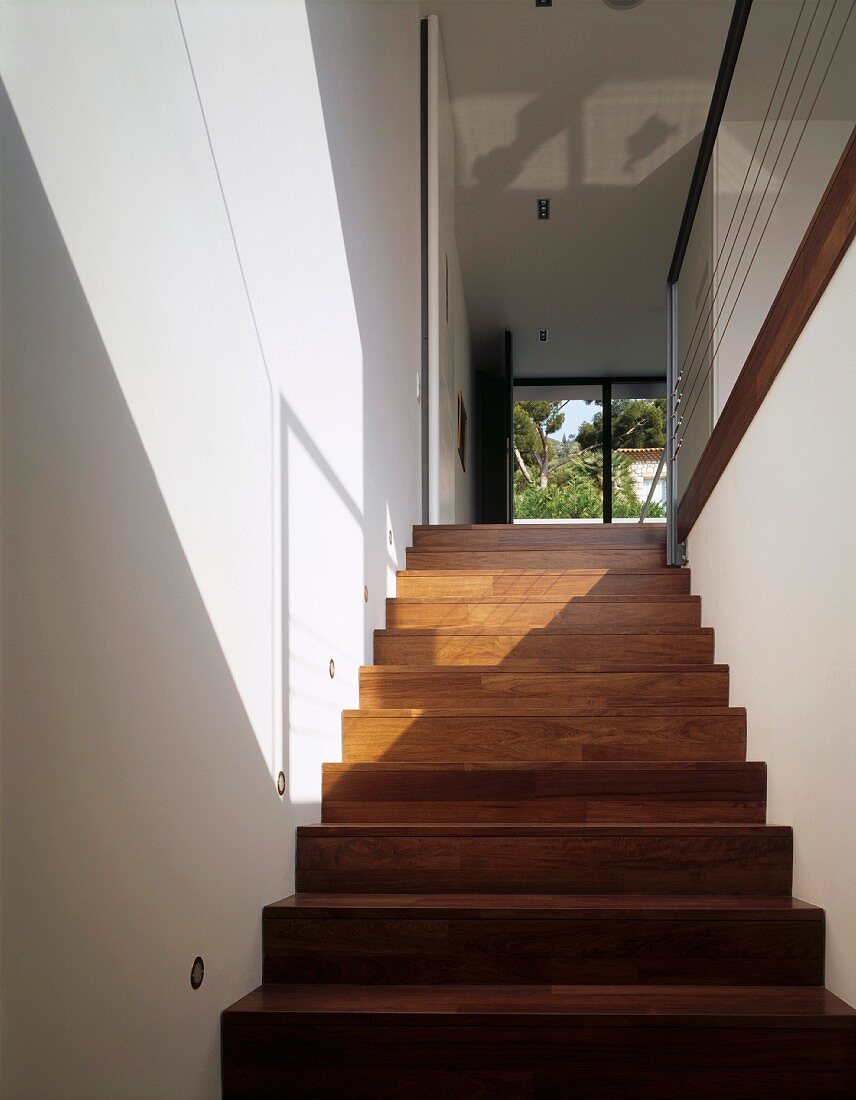 Licht- und Schattenspiel auf Treppenhauswand und Holztreppe