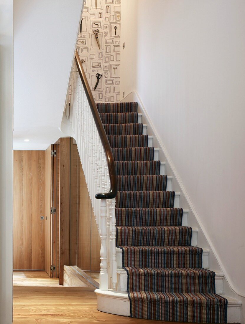 Treppenteppichläufer mit Streifenmuster und weisses gedrechseltes Holzgeländer im modernen Vorraum Treppe