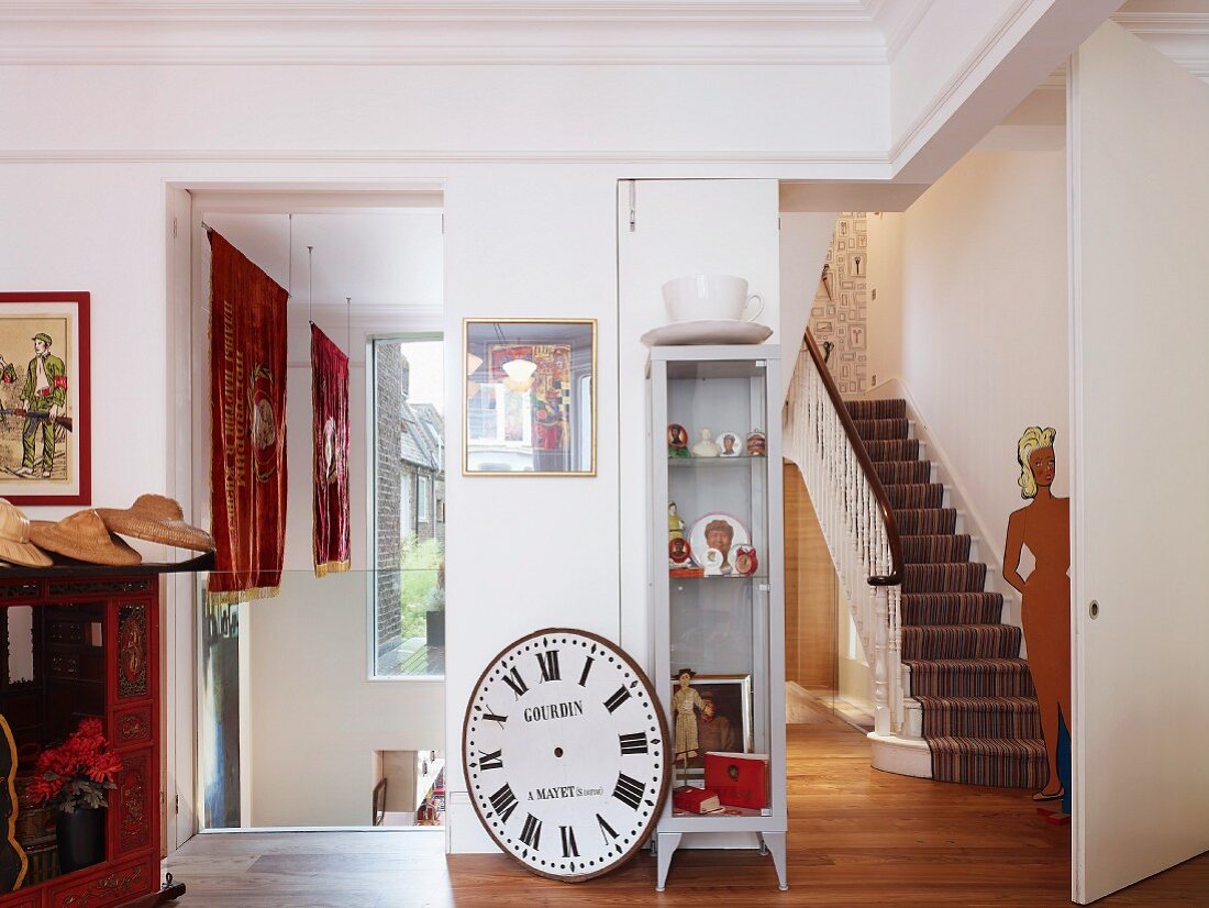 Sammlerstücke im Vorraum einer renovierten Villa mit Blick durch offenen Durchgang auf Treppe
