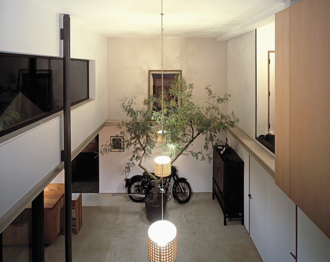 Open-plan, double-height foyer with pendant lamps and parked retro scooter