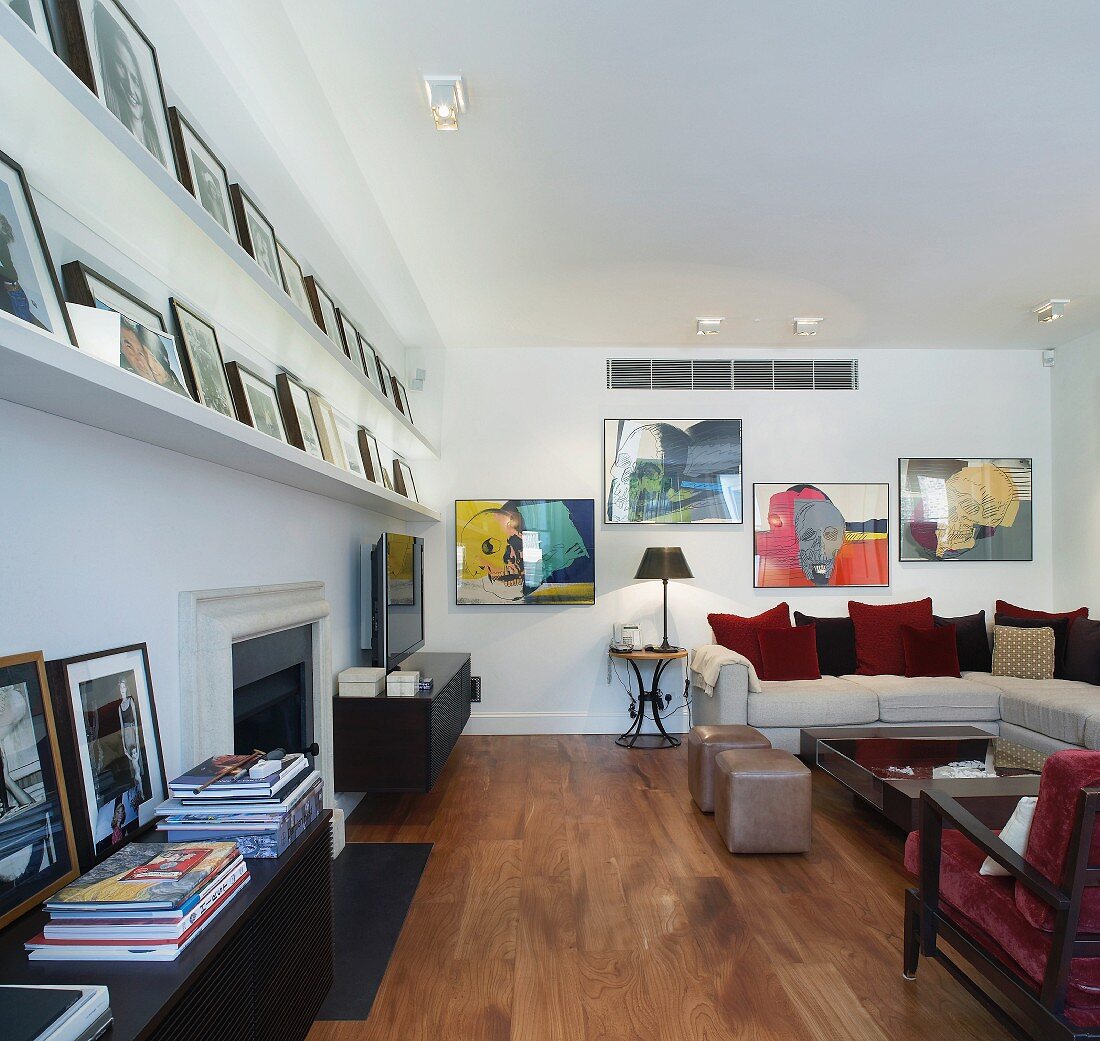 Modern living space with framed pictures on shelves and sofa with scatter cushions