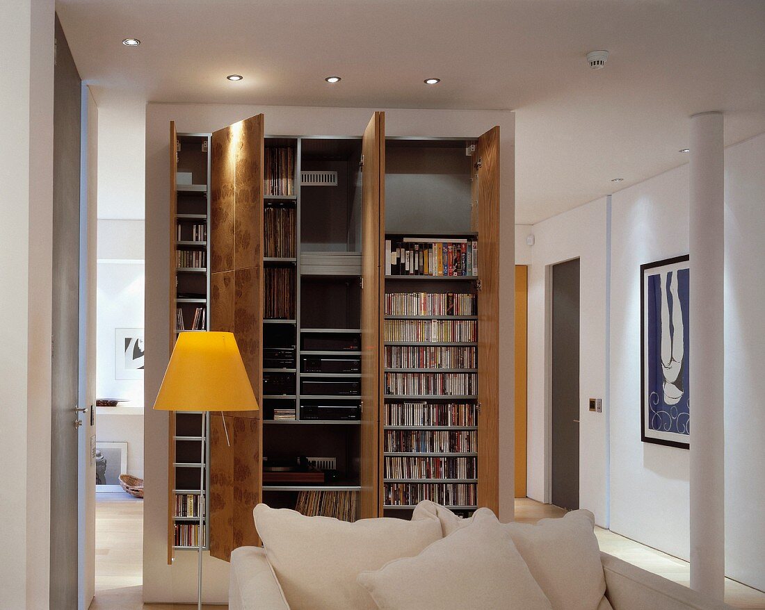 Standard lamps with yellow shade next to sofa, partition behind custom-made stereo cabinet with open doors
