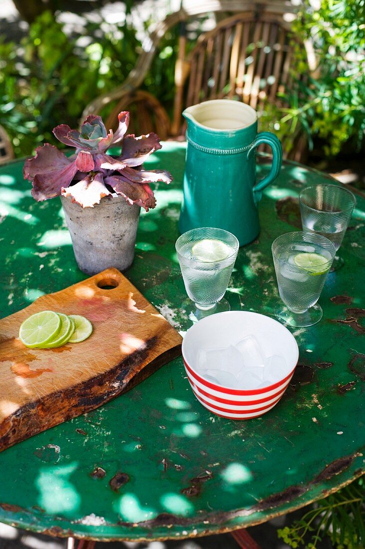 A garden table set with lemonade, a chopping board and a potted plant