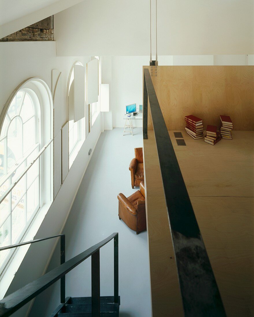 Minimalistische Galerie aus Holz mit Metallgeländer und Blick auf Rundbogenfenster einer Villa