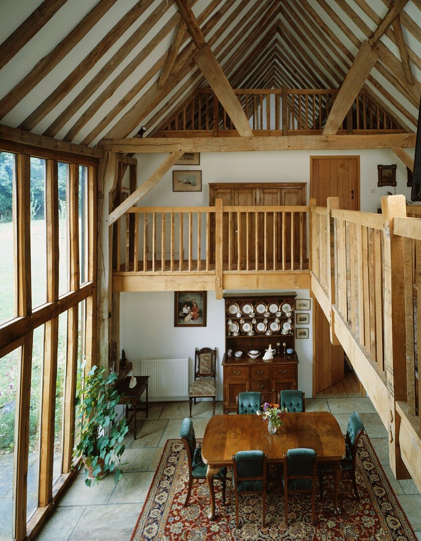 Open-plan house with dining area and views of gallery and rustic roof timbers