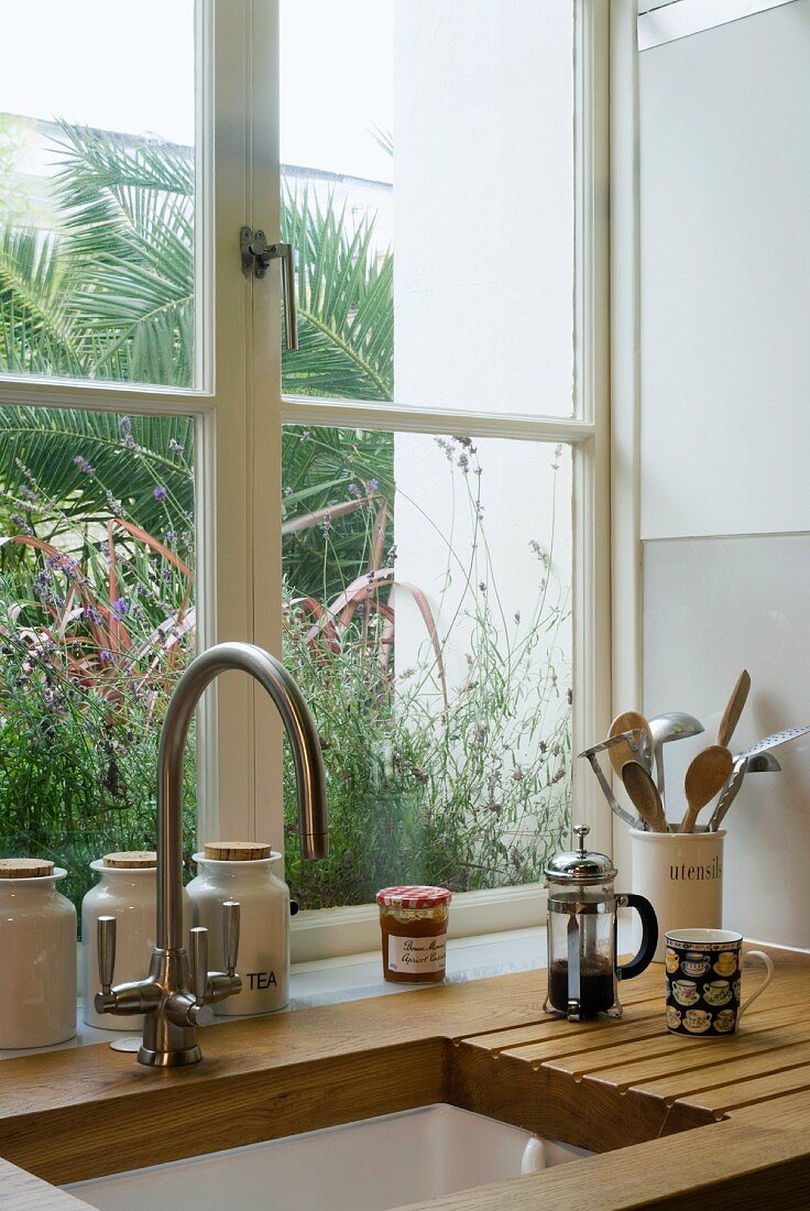 Wooden worktop with kitchen sink and vintage tap fittings in front of window