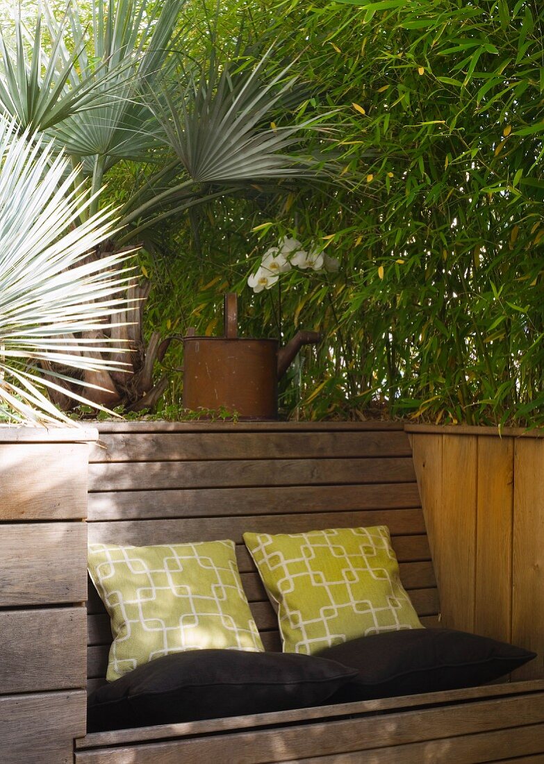 Bambusbeet mit integrierter Holzbank und Kissen auf Terrasse