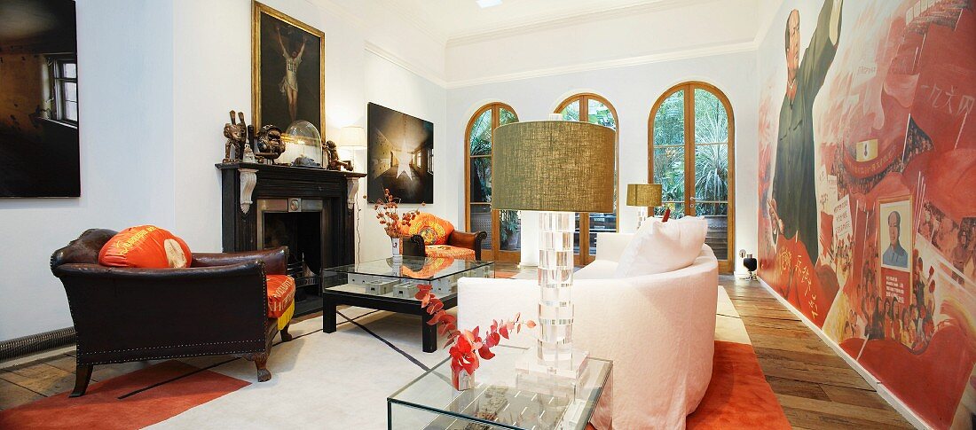 Antiker Ledersessel und helles Sofa vor Wandbild im Wohnraum einer Villa