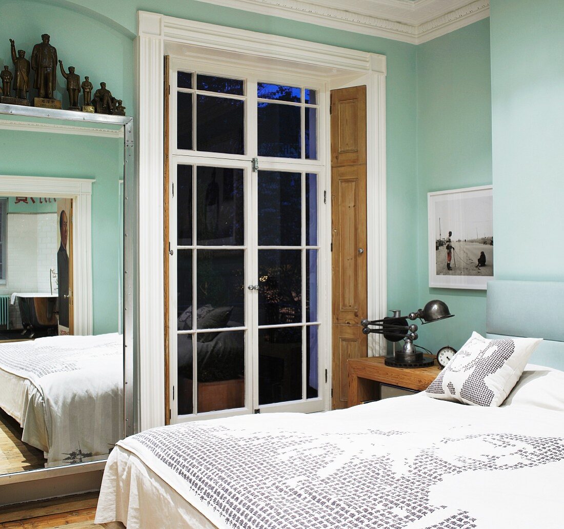 Modernes Doppelbett vor Terrassentür im traditionellen hellblauen Schlafraum