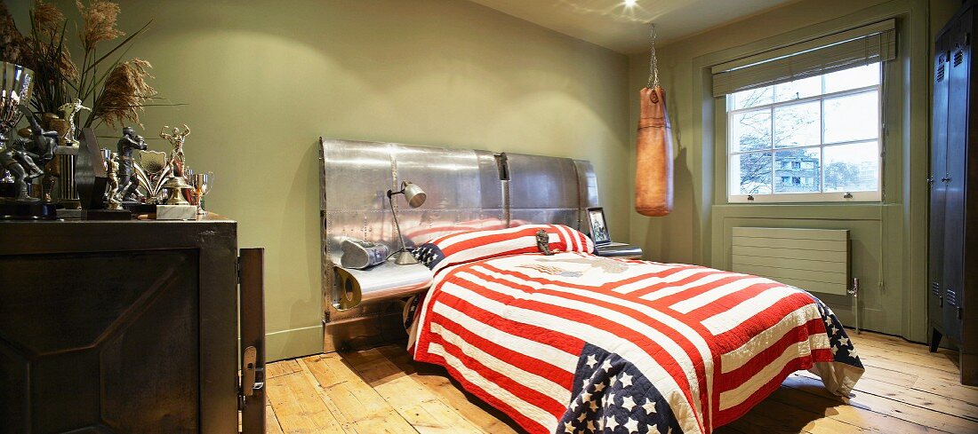 Doppelbett mit englischer Fahne als Tagesdecke im grün getönten Schlafzimmer