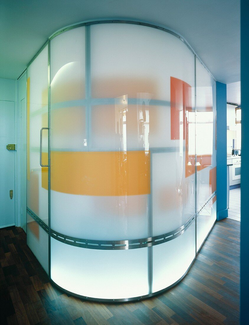 Curved, illuminated glass wall with coloured blocks in foyer