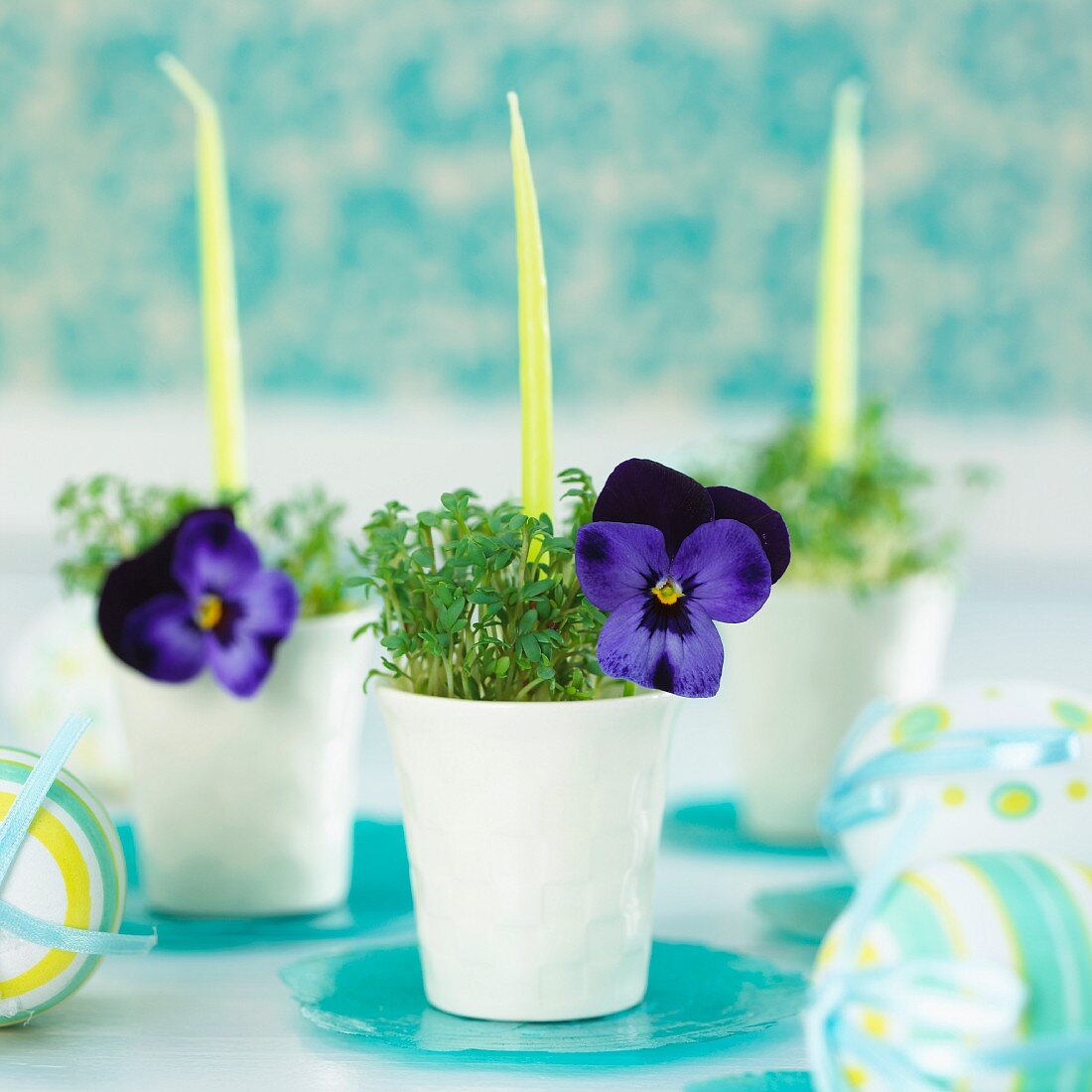 Egg cups planted with cress and decorated with candles and viola flowers