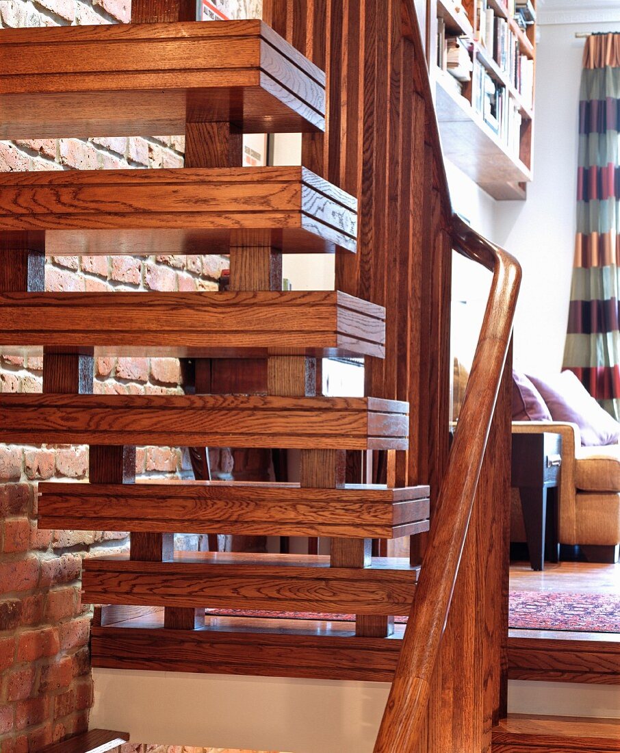 Mit parallelen Nuten verzierte Holzstufen und Holzgeländer an Treppe in Wohnraum