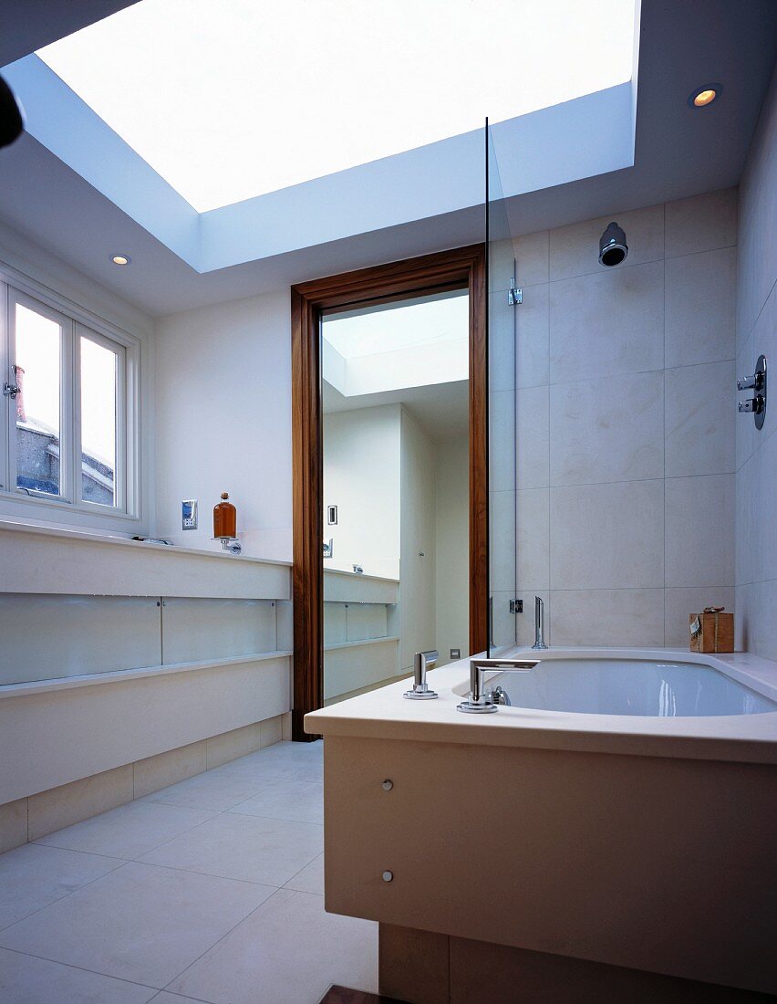 Light, modern bathroom with enormous skylight above floor to ceiling, wood-framed mirror