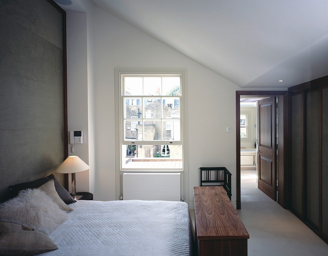 Bad ensuite und englisches Sprossen-Schiebefenster in modernem Schlafzimmer mit Kleiderbank