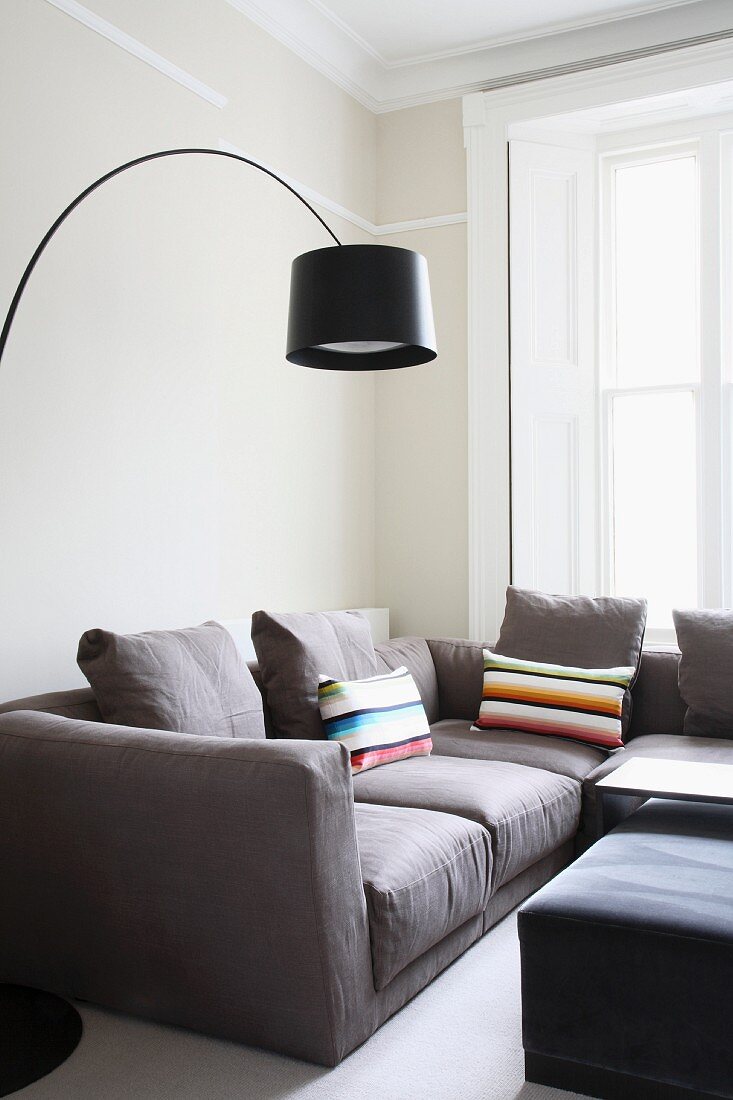 Moderne Wohnraumecke - Bogenlampe mit schwarzem Schirm über hellgrauem Sofa