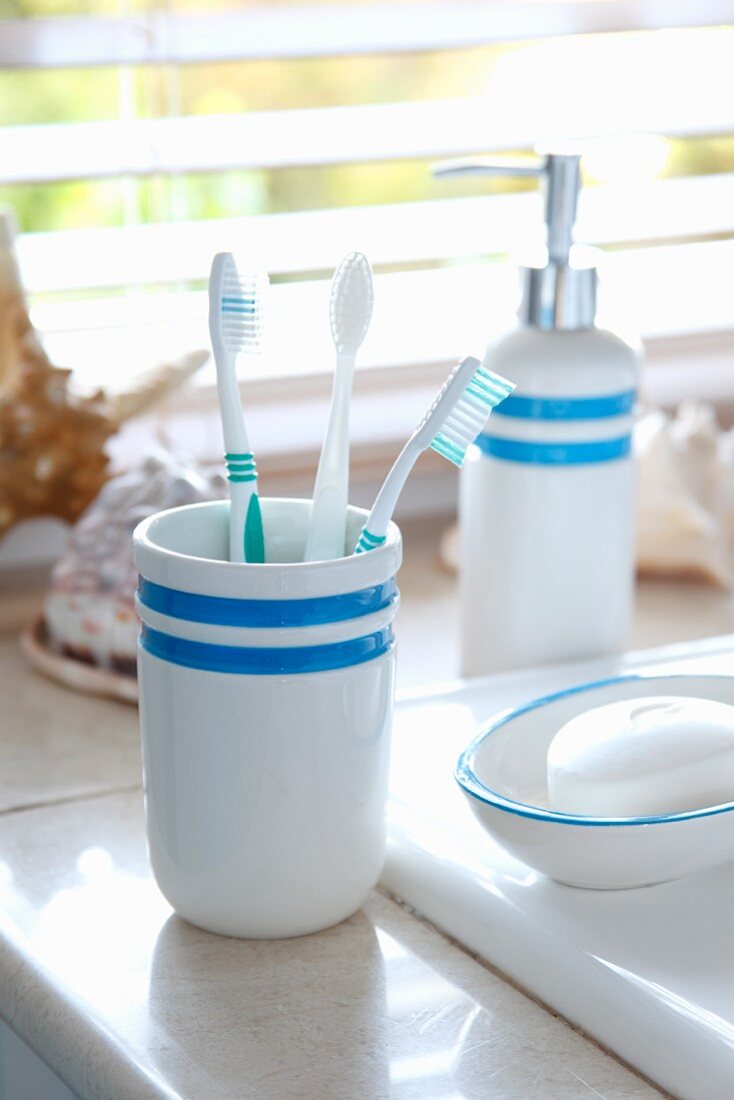 Becher mit Zahnbürsten und Seifenschale auf Waschtisch