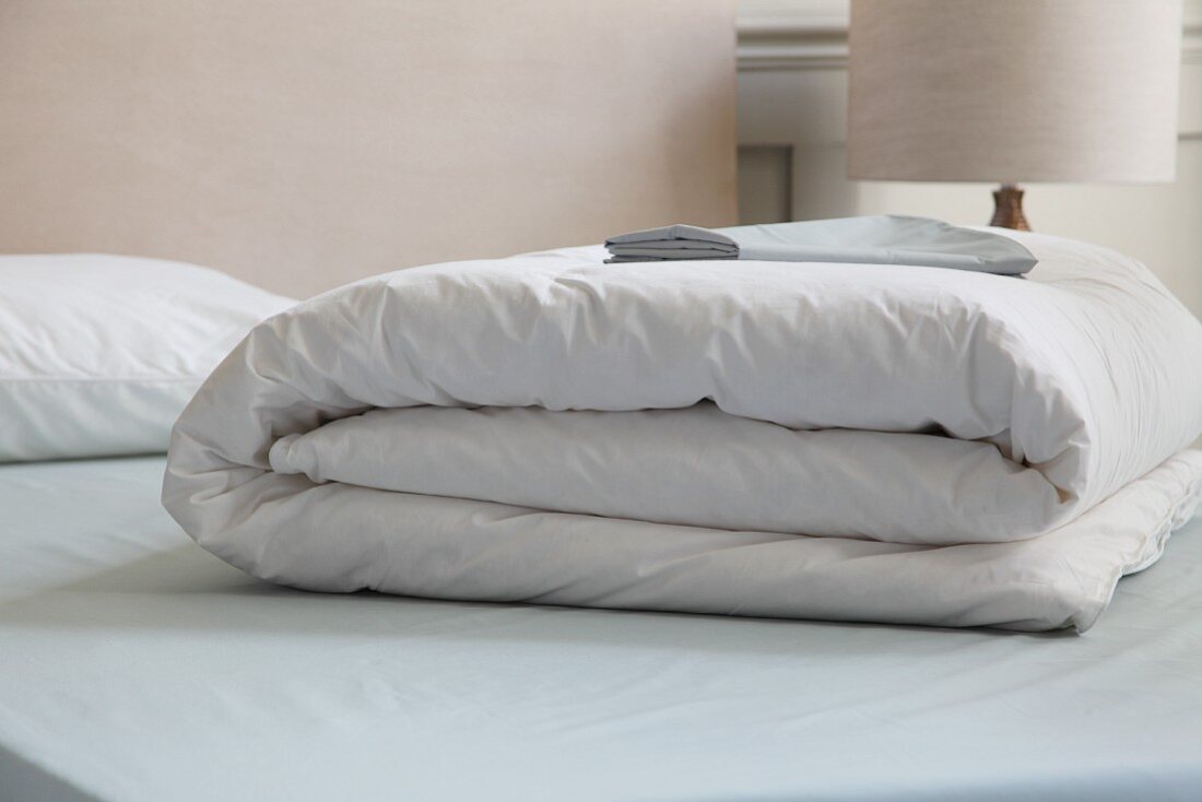 Zusammengelegte weiße Bettdecke auf Bett