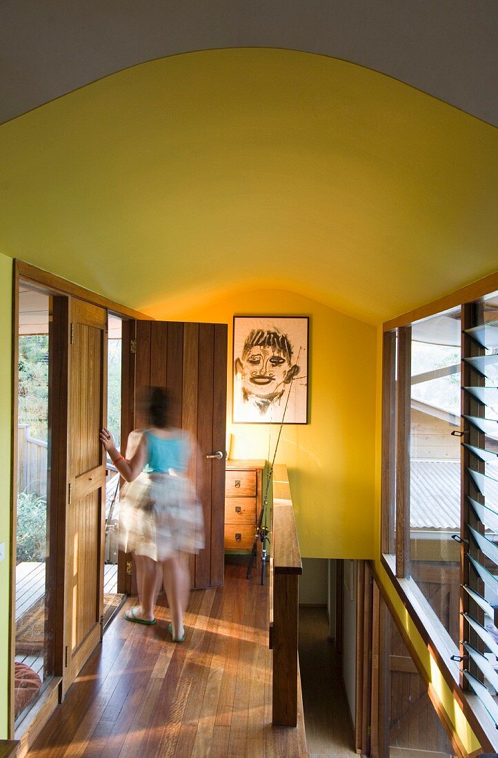 Eine Frau auf dem Flur mit Holzboden und gelben Wänden