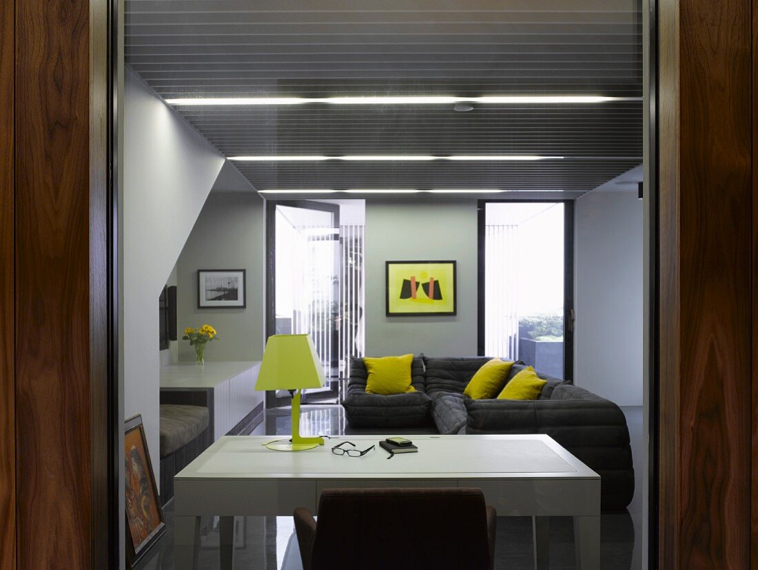 View through open door to white desk and grey sofa