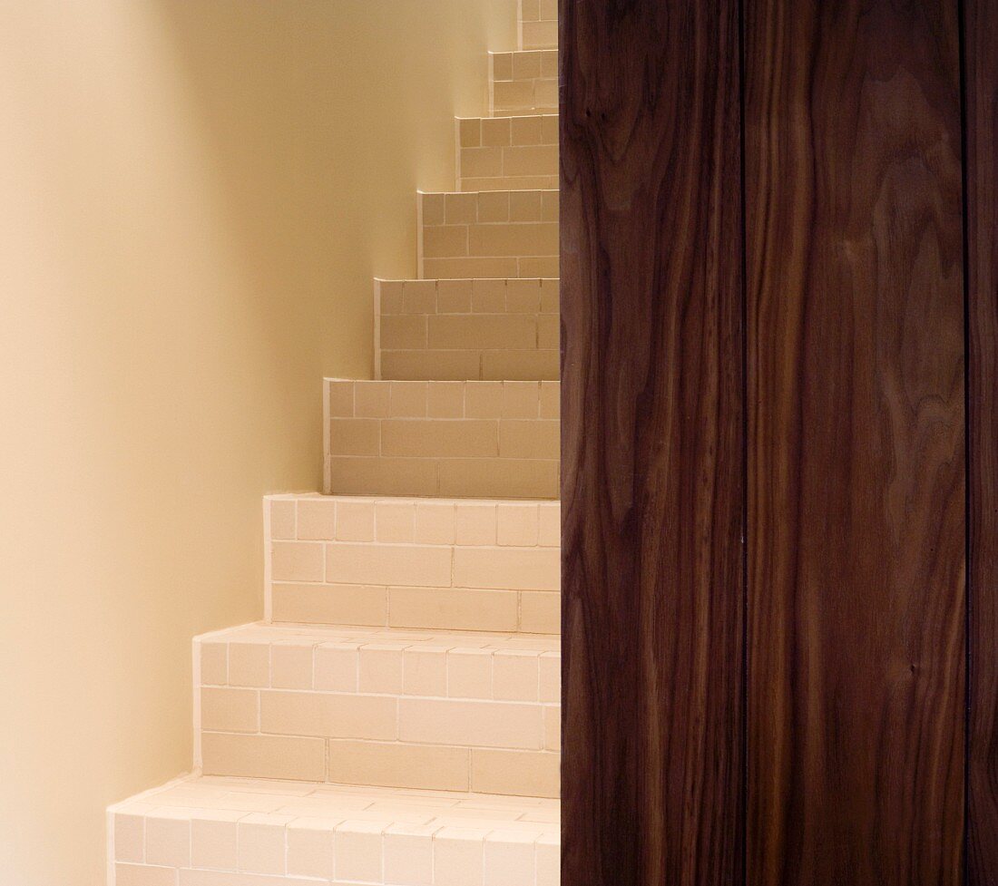 Geflieste Treppenstufen im schmalen Treppenhaus und Holzwand