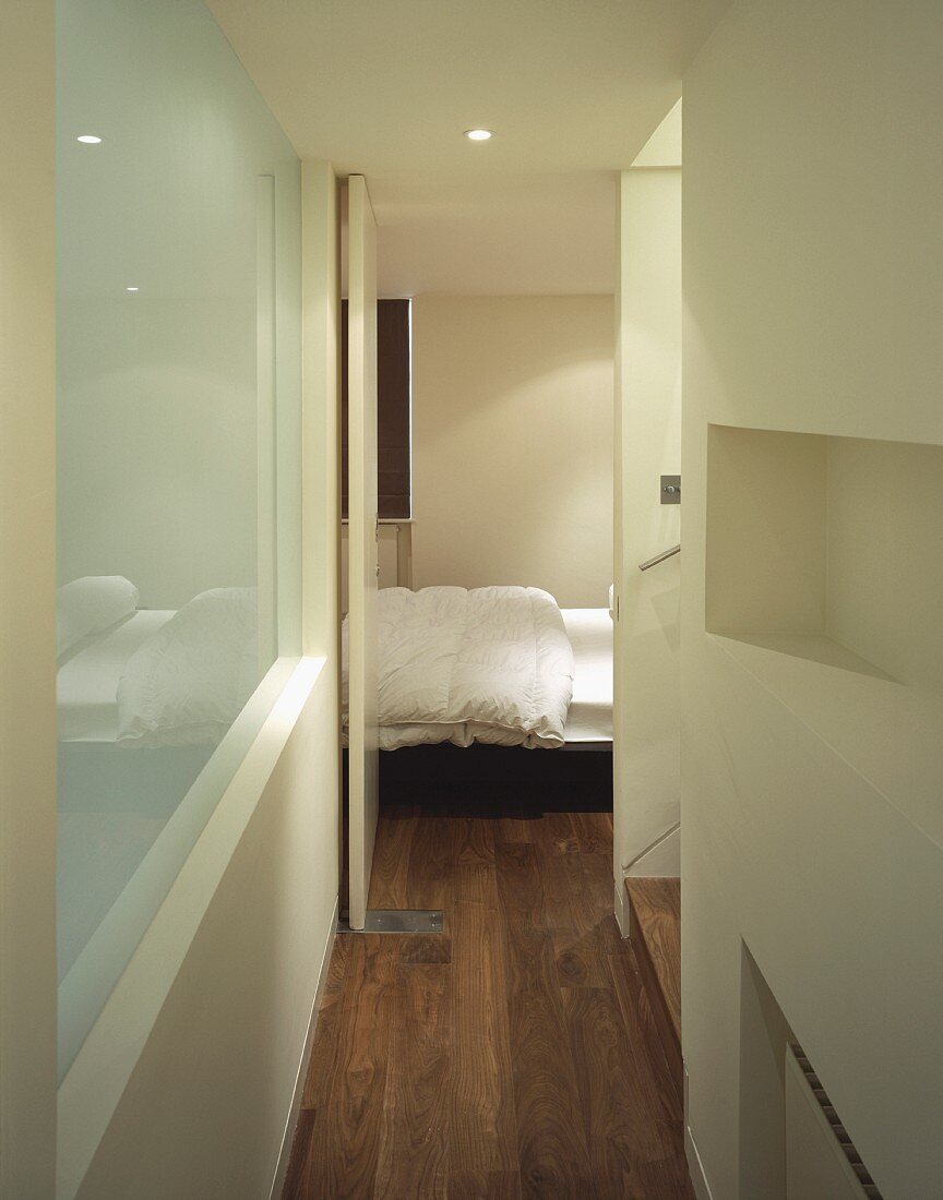 Modern hallway with open bedroom door and view of bed