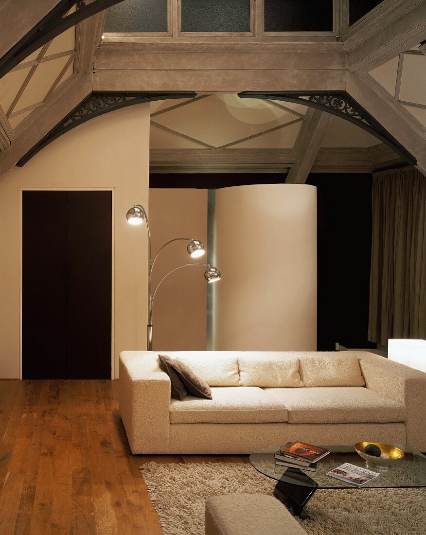 Weisses Sofa und mehrarmige Stehlampe im loftartigen Wohnraum aus Jugendstilzeit