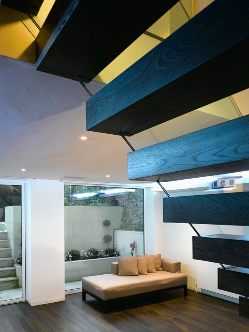 Offene Holztreppe mit moderner Chaiselongue vor raumhohem Fenster im Wohnraum