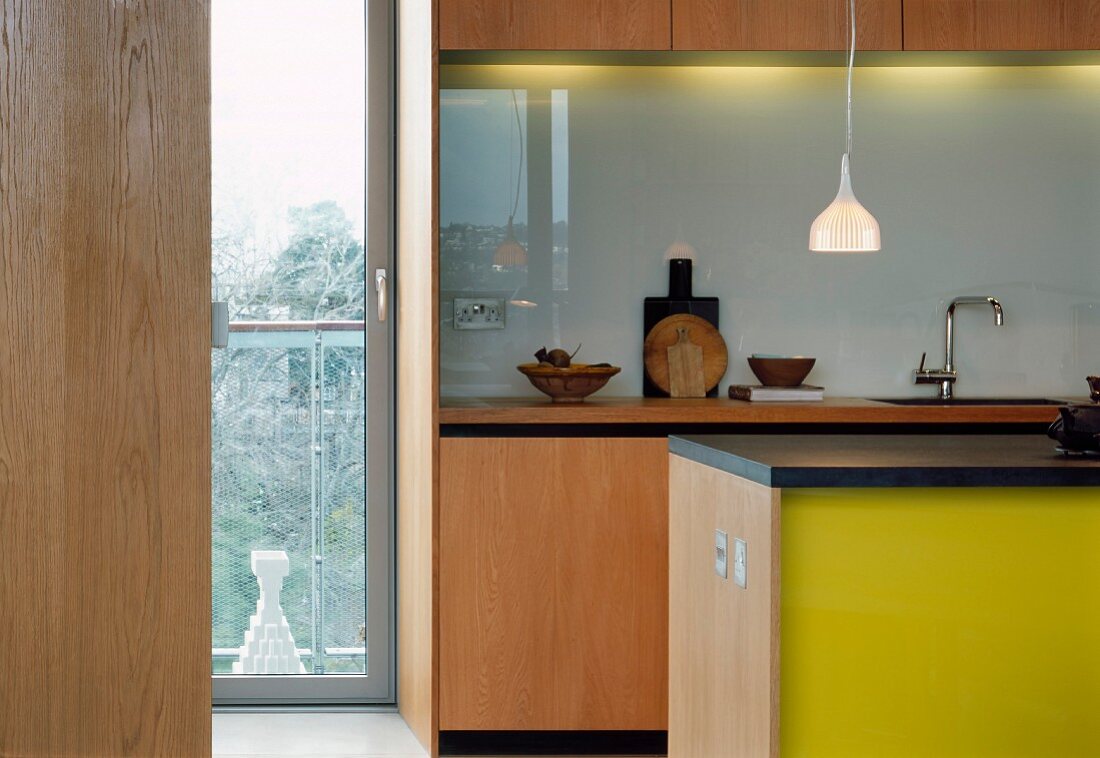 Blick durch offene Tür in moderne Küche mit Theke und gelb lackierter Front