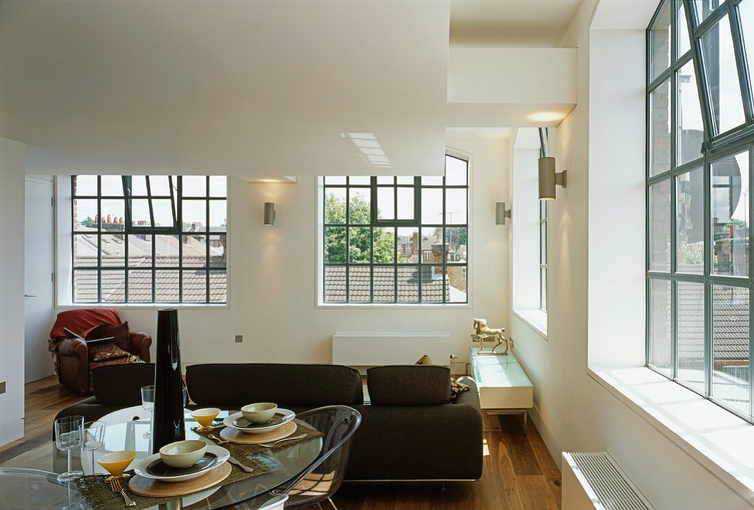 Breakfast in loft-style living space with industrial windows and black metal glazing bars