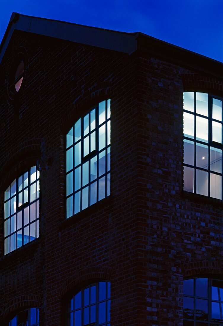 Beleuchtete traditionelle Fabrikhalle in Abendstimmung