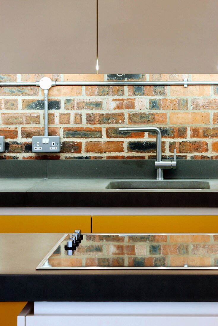 Detail of modern kitchen unit in front of an old brick wall with electrical wiring