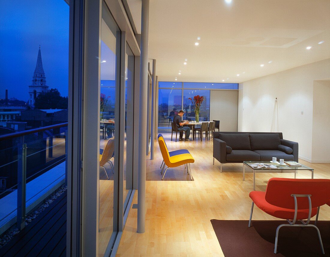 Moderner offener Wohnraum mit farbigen Sesseln und grauem kubischen Sofa