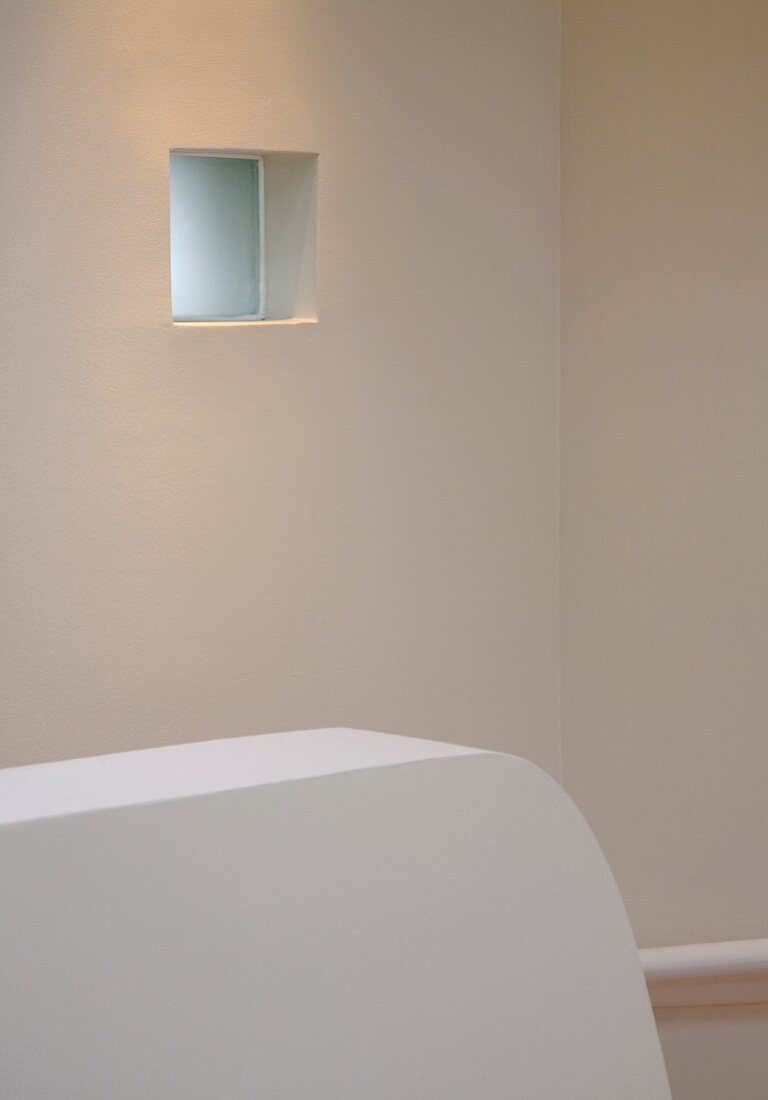 weiße freistehende Brüstungsmauer vor Wand mit kleinem Fenster