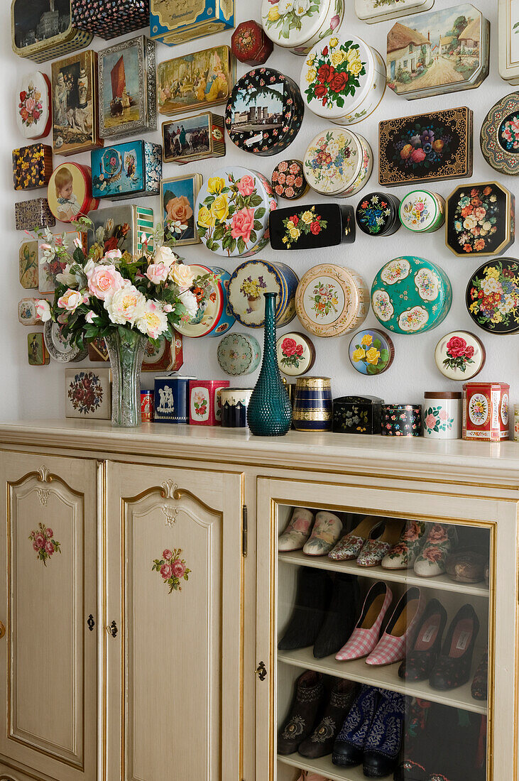 Wall decoration made from vintage tins, shoe cabinet and flower arrangement