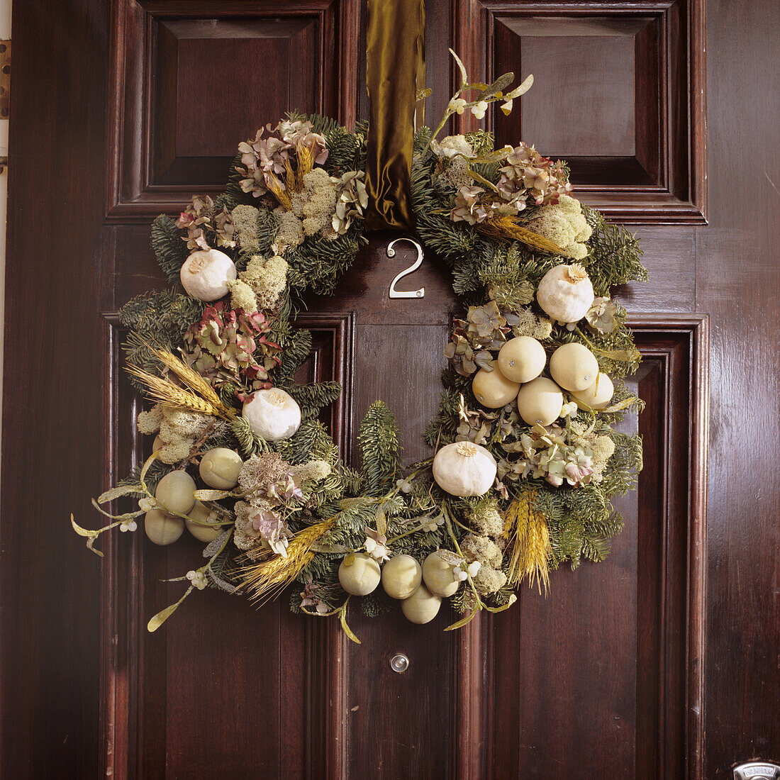 Door wreath made from fir branches, dried flowers and dried fruit on a wooden door