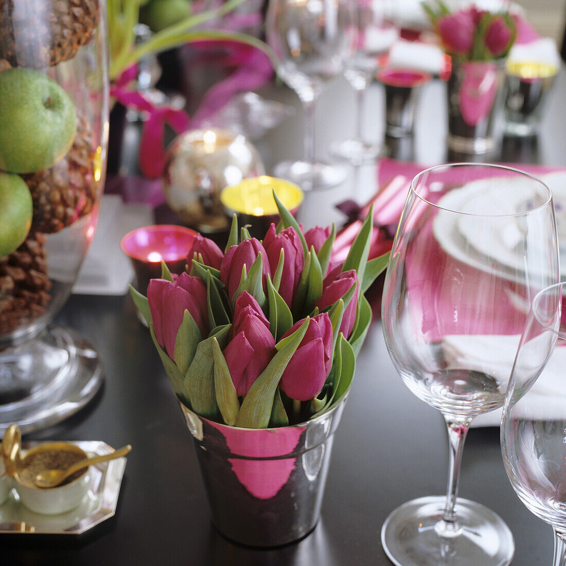 Tulips (Tulipa) in a pot on a laid table with candles and wine glasses