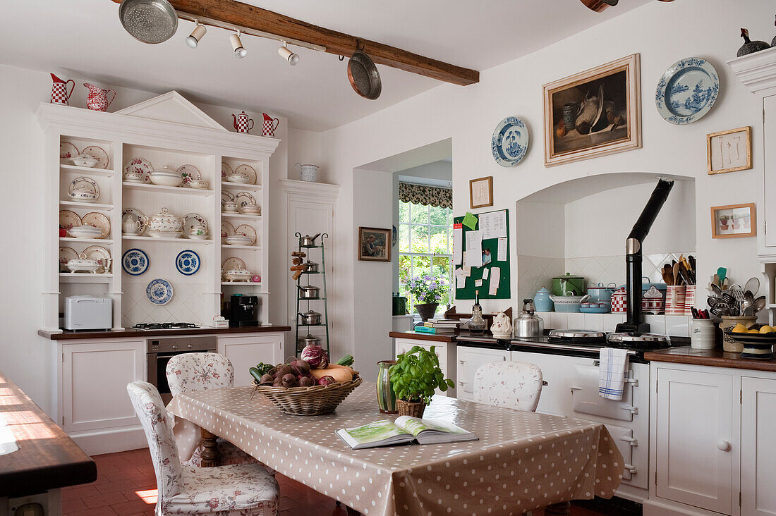 Country-style kitchen with white wooden units and shelves with crockery