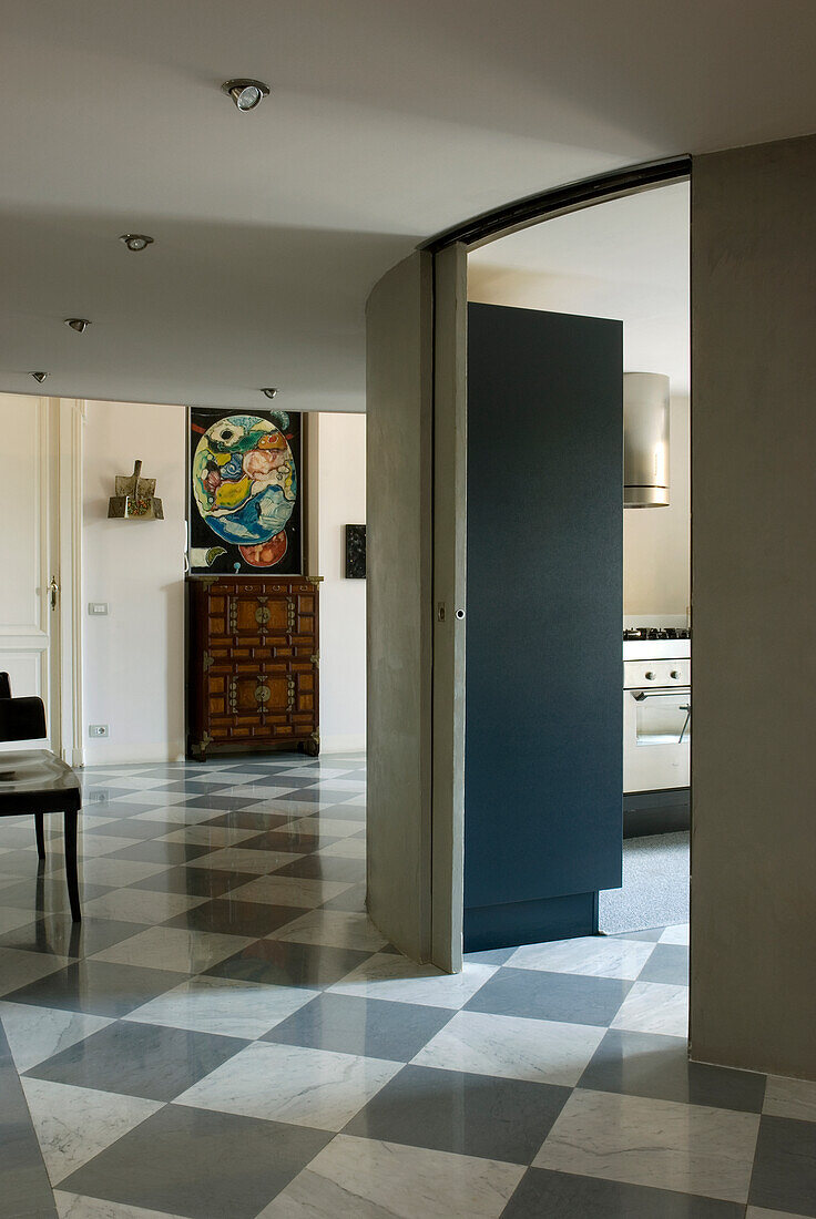 Hallway with sliding door, chequerboard floor and view into the kitchen