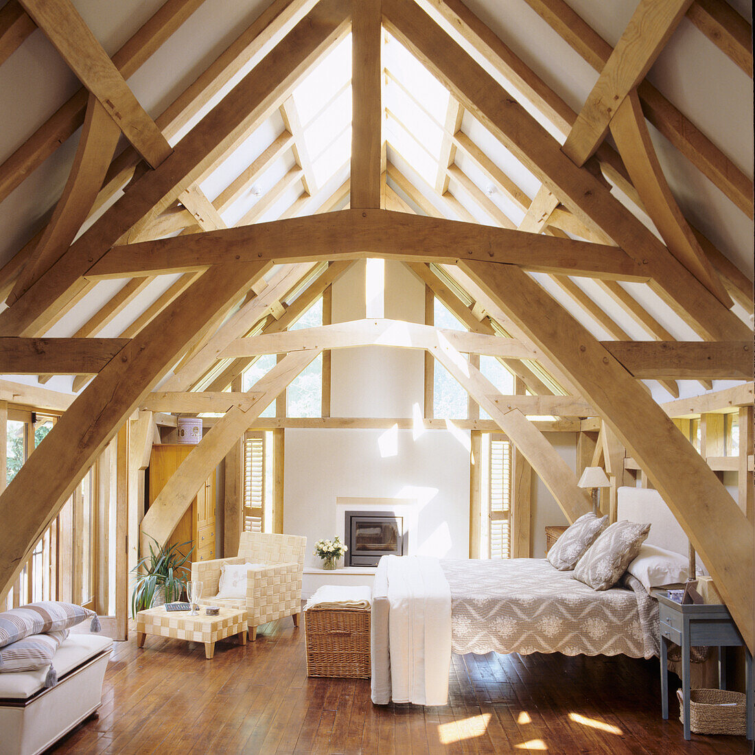 Bright attic bedroom with exposed wooden beams and fireplace