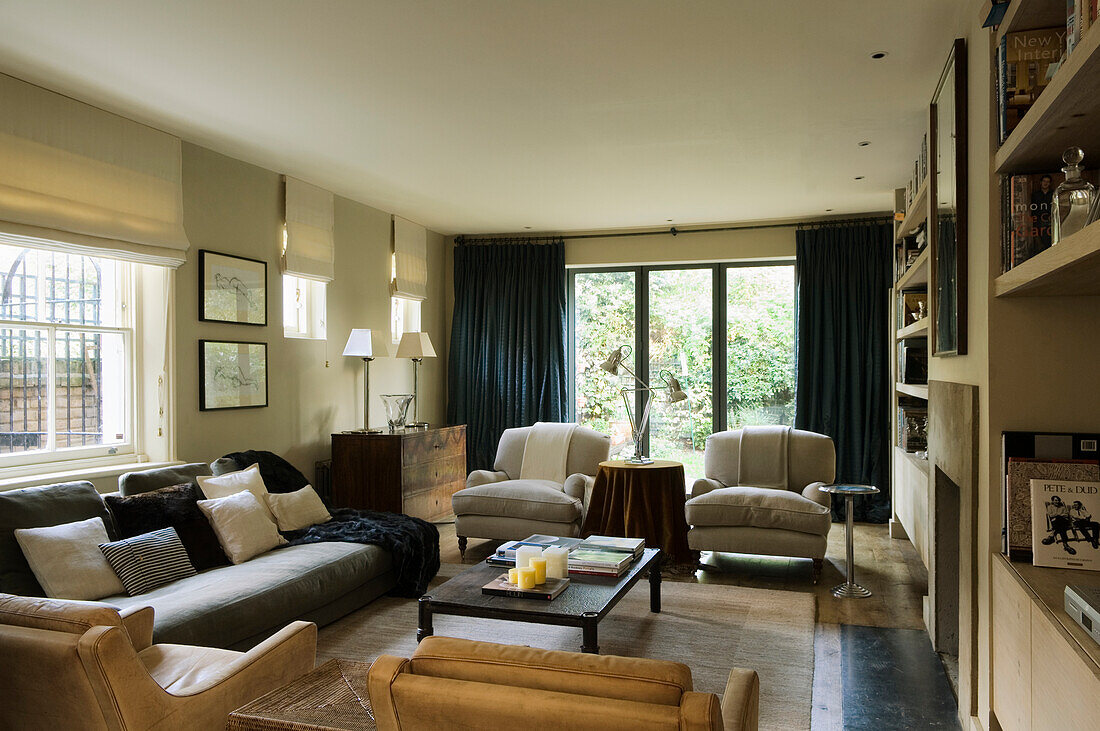 Living room with large windows, beige armchairs and dark curtains